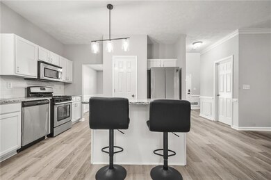 Kitchen featuring appliances with stainless steel finishes, white cabinetry, light wood-type flooring, a center island, and a breakfast bar