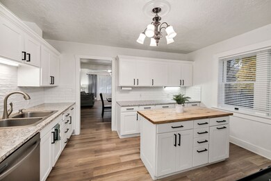 Kitchen featuring dishwasher, pendant lighting, light wood-style floors, white cabinets, and a textured ceiling