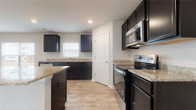 Kitchen featuring electric range oven, light wood-