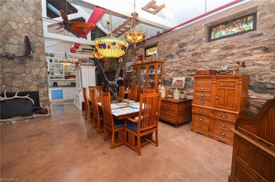 Dining Room Area.  Notice Stained Glass Windows on Side.  Also There Is A Wood Stove for Back Up Heat.