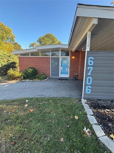 Doorway to property with brick siding and a lawn