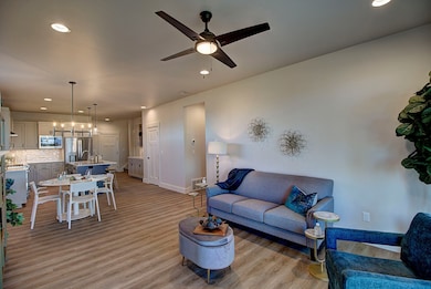 Living room with light wood finished floors, baseboards, ceiling fan, and recessed lighting. Tour and photos are a depiction of the Primrose plan