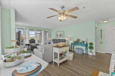 Living area featuring wood finished floors, a ceiling fan, baseboards, and a textured ceiling