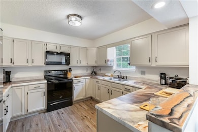 Kitchen featuring a sink, a textured ceiling, blac