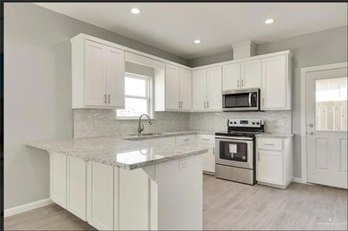 Kitchen with stainless steel appliances, a peninsula, white cabinets, and recessed lighting