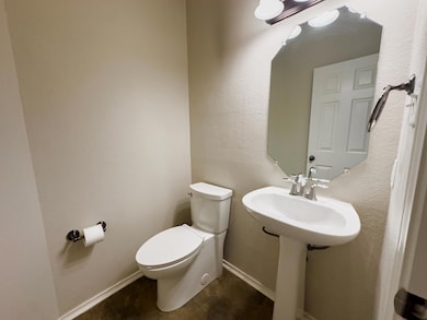 Half bathroom featuring a textured wall and toilet