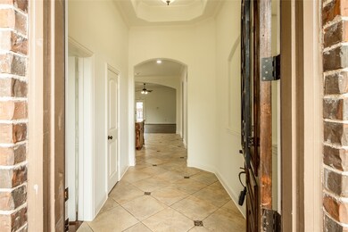 Hallway featuring arched walkways, light tile patterned flooring, and ornamental molding