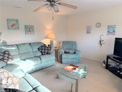 Carpeted living area with ceiling fan and baseboards