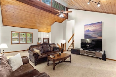 Living area with wood ceiling, light carpet, stairs, high vaulted ceiling, and a ceiling fan