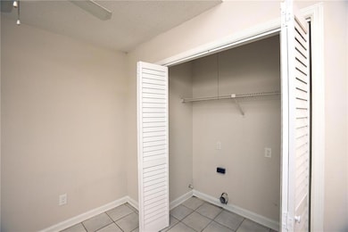 Laundry room with a textured ceiling, light tile patterned floors, and ceiling fan