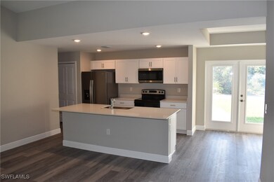 Kitchen with baseboards, appliances with stainless steel finishes, a sink, and white cabinets
