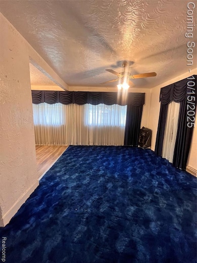 Unfurnished bedroom with a textured wall, a textured ceiling, and a ceiling fan