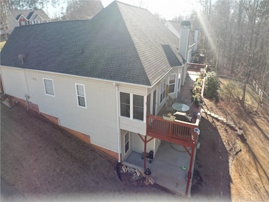 Back of property featuring a shingled roof, a deck