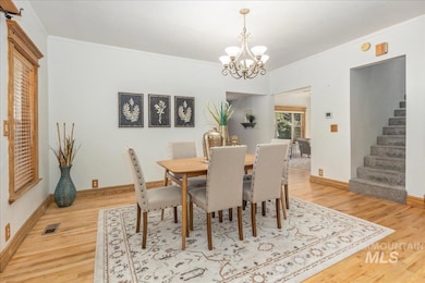 Dining room featuring a chandelier, crown molding, light wood-type flooring, and stairway
