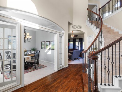 Foyer entrance featuring a high ceiling, wood finished floors, stairs, a glass doors to dining room.