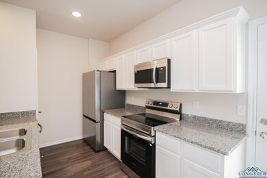 Kitchen with stainless steel appliances, dark wood-type flooring, white cabinets, recessed lighting, and baseboards