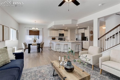 Living room with a chandelier, stairway, light woo