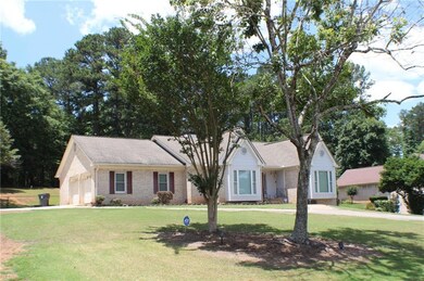 Ranch-style home featuring a front yard, brick siding, and an attached garage