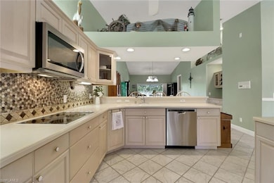 Kitchen featuring pendant lighting, stainless steel appliances, tasteful backsplash, glass insert cabinets, and light countertops