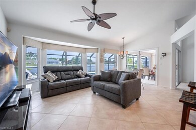 Living room featuring a chandelier, lofted ceiling, a water view, light tile patterned floors, and ceiling fan