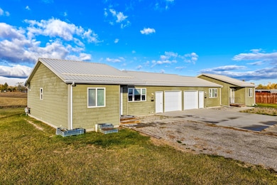 View of front of property with a metal roof, driveway, a front yard, and an attached garage