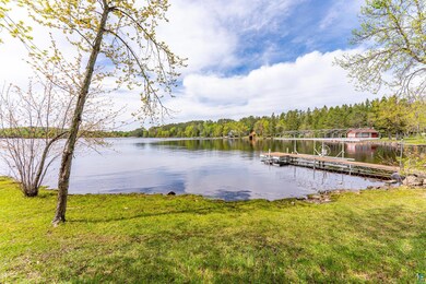 Dock featuring a water view, a view of trees, and a lawn