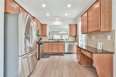 Kitchen featuring appliances with stainless steel finishes, a sink, light wood-style flooring, recessed lighting, and tasteful backsplash