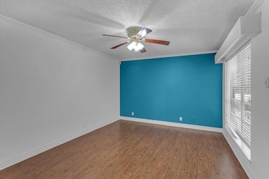 Spare room with crown molding, plenty of natural light, ceiling fan, and dark hardwood / wood-style floors