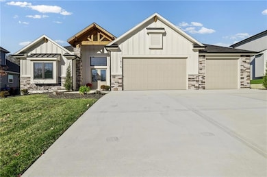 Modern farmhouse featuring stone siding, board and batten siding, concrete driveway, an attached garage, and a front yard