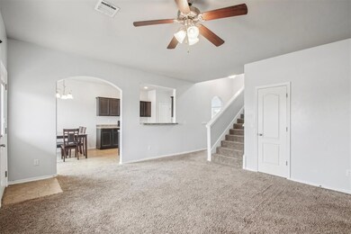 Unfurnished living room featuring ceiling fan with notable chandelier and light colored carpet