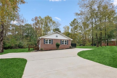 Single story home featuring a front lawn, brick siding, a deck, and concrete driveway