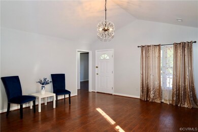 Sitting room with dark wood-type flooring, a chand