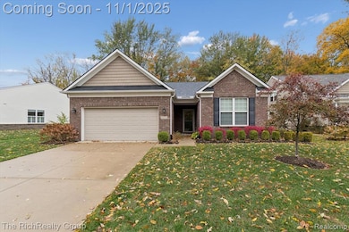 Ranch-style house with a front yard, concrete driveway, brick siding, and an attached garage