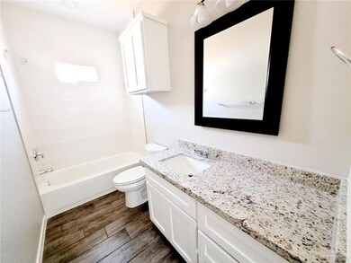 Bathroom with bathing tub / shower combination, toilet, wood finished floors, and vanity