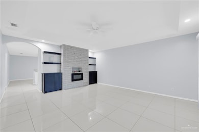 Unfurnished living room with a ceiling fan, arched walkways, recessed lighting, light tile patterned flooring, and a fireplace