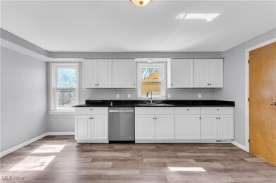 Kitchen with a sink, baseboards, light wood-type flooring, and dishwasher