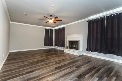 Unfurnished living room with ornamental molding, a fireplace, dark wood-type flooring, and a ceiling fan