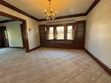 Unfurnished room featuring ornamental molding, carpet, and a notable chandelier