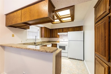 Kitchen featuring light stone counters, sink, whit