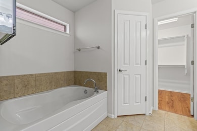 Bathroom with a bath, light tile patterned floors, and a spacious closet