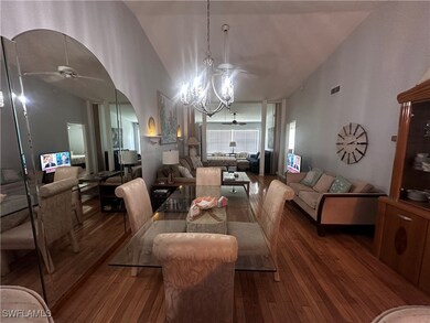 Dining area with ceiling fan, hardwood / wood-style floors, arched walkways, a chandelier, and high vaulted ceiling