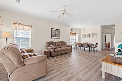 Living room with light wood-style flooring, ceiling fan, a chandelier, and baseboards
