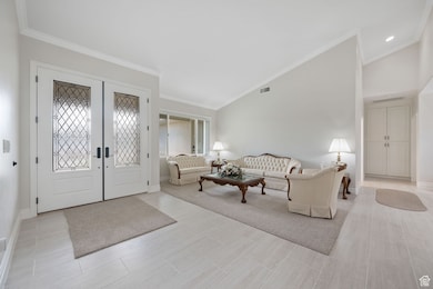 Main Entry / Living room featuring ornamental molding, french leaded-glass entry doors, high vaulted ceiling, and 3-tone paint, tile & carpet flooring