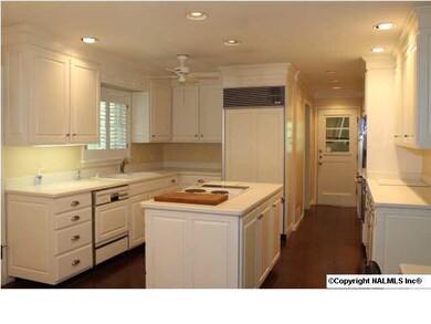 Kitchen with Corian countertops, island with cooktop, Jenn-Aire refrigerator