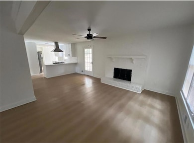 Unfurnished living room featuring dark wood-type flooring, ceiling fan, and a fireplace