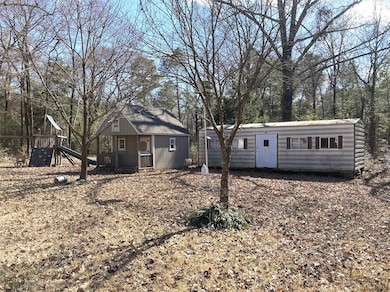 Back yard has a mobile home storage building, playhouse and play ground set.