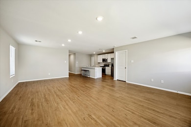 Open-concept living features vinyl flooring and neutral walls, connecting to a modern kitchen with island.