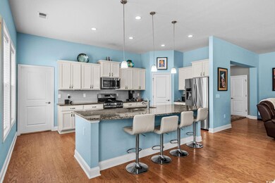 Kitchen with appliances with stainless steel finishes, a kitchen breakfast bar, light wood-style flooring, an island with sink, and white cabinets