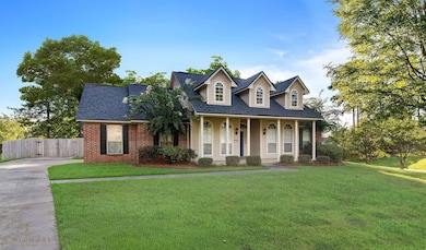Cape cod house with a shingled roof, a porch, driveway, brick siding, and a gate