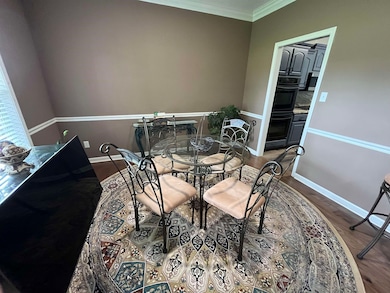 Dining area with wood-type flooring and crown mold